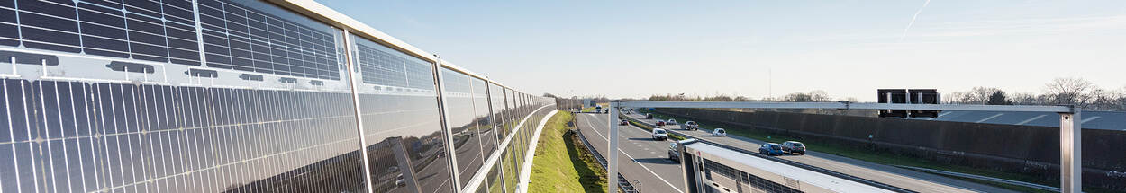 Geluidswal met zonnepanelen langs de snelweg.