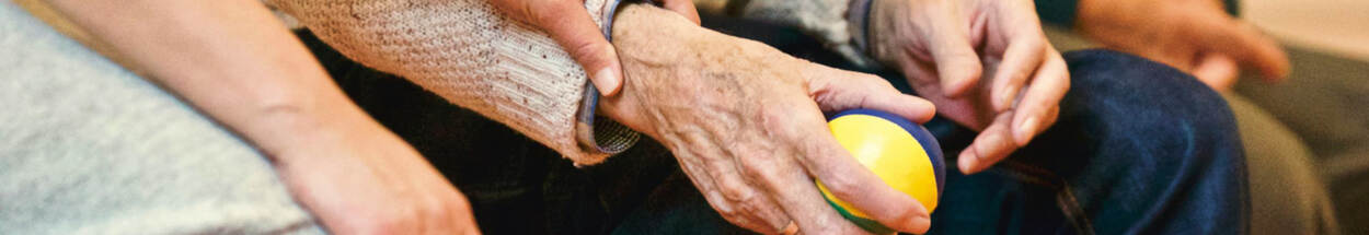 Jonge hand op oude hand die bal vasthoudt