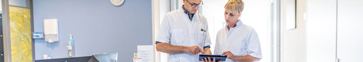 verpleegkundigen kijken op tablet in gang ziekenhuis
