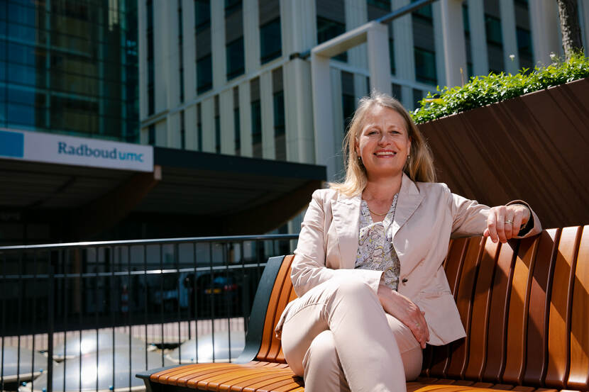 Bertine Lahuis op een bankje voor de ingang van het Radboudumc